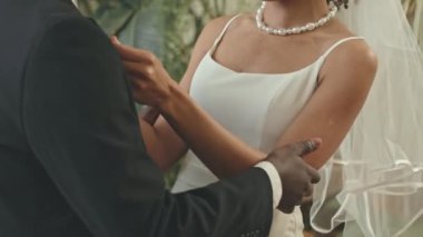 Beyaz gelinlik ve duvak giymiş güzel bir kadın ve düğün töreninden önce şefkatle kucaklayan sevgili Afrikalı Amerikalı kocası.
