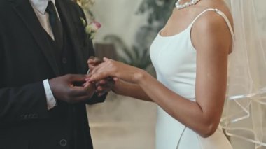 Geleneksel tören sırasında siyah takım elbiseli siyah damadın sevgili gelininin parmağına yüzük takması.