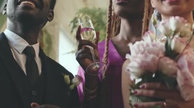 Yeni evli Afro-Amerikan çift ve bir bardak şampanyayla genç nedimelerin düğün üstüne fotoğraf çekimleri.