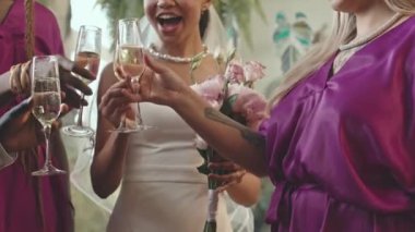 Afro-Amerikan yeni evli çiftin ve mor elbiseli iki genç nedimenin kadehlerini şampanya kadehleriyle tören sonrası kaldırması.