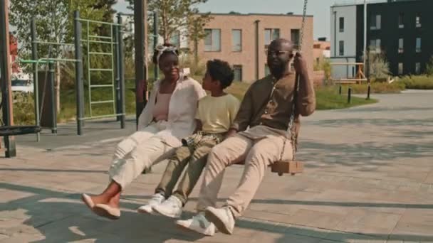 Schnappschuss Einer Modernen Afroamerikanischen Dreierfamilie Die Gemeinsam Auf Spielplatzschaukeln Schaukelt — Stockvideo