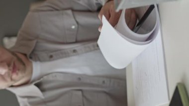 Kafkasyalı genç bir iş adamının resmi. Sayfalar dolusu basılı iş sözleşmesine bakıyor ve ofiste evrak işleriyle uğraşırken imzasını atıyor.