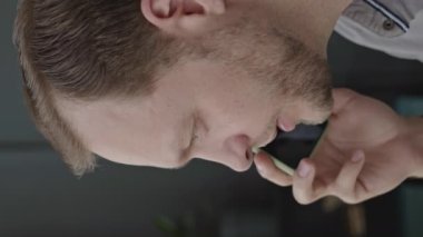 Kafkasyalı genç işadamının iş yerinde telefon görüşmesi yaparken dikey görüntüsü