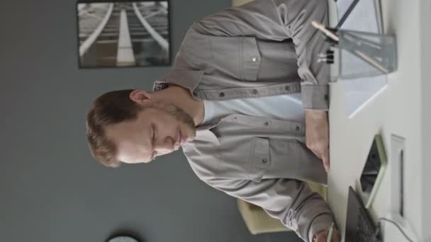 Pionowe Ujęcie Młodego Białego Mężczyzny Korzystającego Laptopa Siedzącego Minimalistycznym Biurze — Wideo stockowe