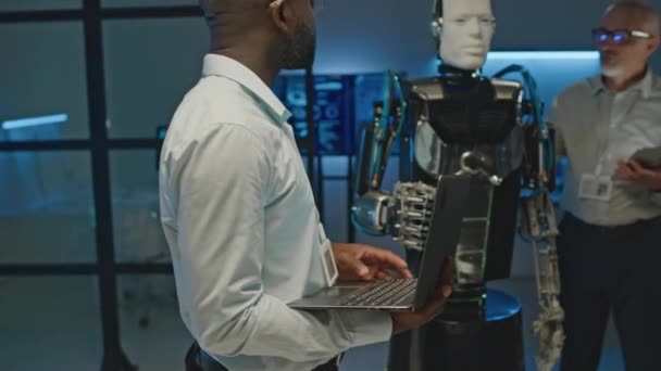 Średnie Ujęcie Czarnego Dewelopera Kolegą Testującym Człowieka Jak Robota Laboratorium — Wideo stockowe