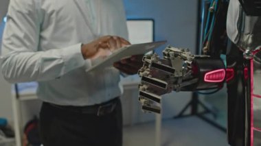 Bilim laboratuarında dijital tablet ile insan robotu kullanan tanınamayan teknoloji geliştiricisinin görüntüsü.