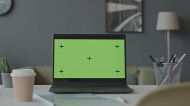 Modern ofisteki beyaz masada yeşil renkli anahtar ekranlı bir dizüstü bilgisayar görüntüsü yok.