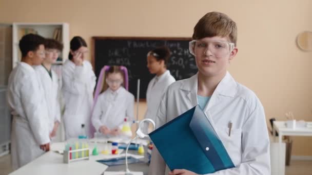 Středně Pomalý Portrét Bělošského Školáka Laboratorním Plášti Bezpečnostních Brýlích Složkou — Stock video