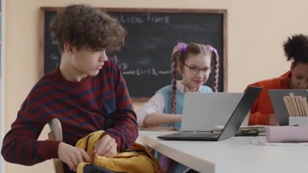 彼のバッグからポータブルハードドライブを取り出し それをラップトップコンピュータに接続し 現代のクラスの他の学生とプログラミングを研究するカーリーハイヤードBiracial Prboyのウエスト — ストック動画