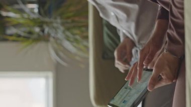 Ofiste çalışırken dijital tablet kullanan tanınmayan iş çiftinin dikey kırpılmış görüntüsü