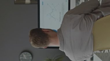 Modern ofisteki bilgisayar bilgisayarında finansal veriler üzerinde çalışan düşünceli bir adamın dikey arka plan görüntüsü