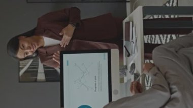 Genç çift ırklı kadın ofis çalışanının iş yerinde iş arkadaşlarıyla konuşurken orta boy görüntüsü.