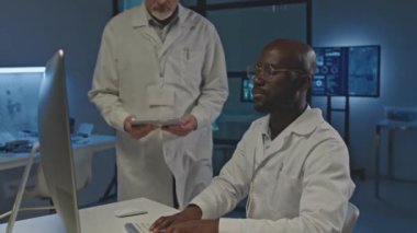 Gece laboratuvarda çalışırken bilgisayar kullanan iki profesyonel elektronik mühendisinin orta boy görüntüsü.