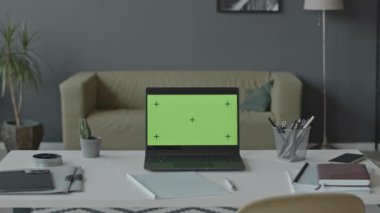 Ofis işyerinde laptopla çekilen ve beyaz masada yeşil ekran olan kimse yok.