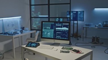 Anakart ve bilgisayar monitörüyle modern elektronik mühendisliği işyerinde çekilen hiç kimse, karanlık ofisteki mavi ışıklı beyaz masada veri bilgisini göstermiyor.