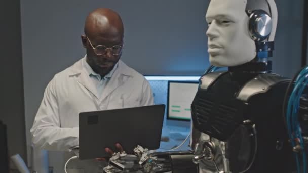 Średnie Ujęcie Skoncentrowanego Inżyniera Robotyki Afroamerykanów Używającego Laptopa Podczas Pracy — Wideo stockowe