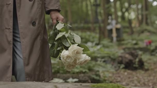 Strzał Nierozpoznawalnej Kobiety Długim Płaszczu Stojącej Bukietem Białych Róż Cmentarzu — Wideo stockowe