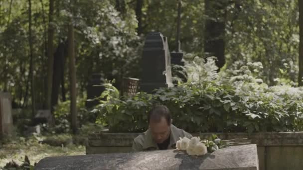 Θλιμμένος Χήρος Κάθεται Στον Τάφο Στο Νεκροταφείο Βάζοντας Κεφάλι Του — Αρχείο Βίντεο
