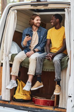 Kamp sırasında kamyonette dinlenen iki arkadaş, cep telefonu kullanıyorlar ve konuşuyorlar.
