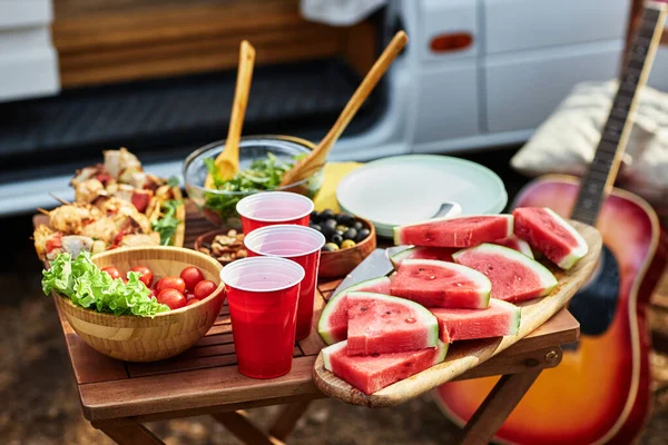 新鮮なスイカのクローズアップ ピクニックの屋外テーブル上の肉と野菜サラダ — ストック写真