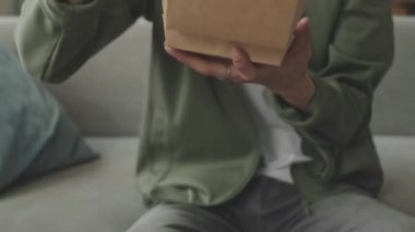 Asyalı, sarıya boyanmış saçları olan, gündüz vakti evde lezzetli hamburgerin tadını çıkaran adam.