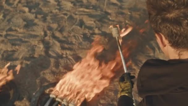若い男性アーティストが特別な消防隊員を燃やし 夕日には砂浜で極端な火のショーの準備をしているショットの上に — ストック動画