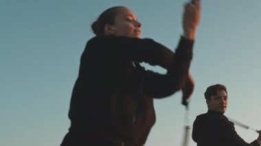 İki beyaz profesyonel sirk sanatçısının yaz festivalinde gün batımında gösteri yaparken ateşle hokkabazlık yaptığı ve dans ettiği orta boy bir fotoğraf.