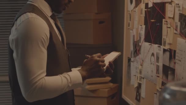 Tilt Shot Serious African American Detective Making Notes While Analyzing — Vídeo de stock