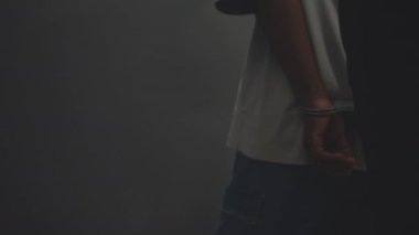 Tanınmayan bir polis memuru tutuklu bir adama hücreye kadar eşlik ediyor ve ellerindeki kelepçeleri çıkarıyor.