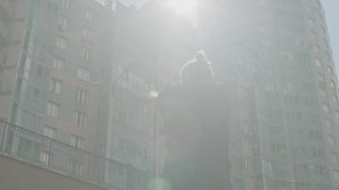 Düşük açılı mercek, şehirde güneşli bir sokakta antrenman yaparken akrobatik adamın kollarını ısıtırken görüntüsünü çekti.