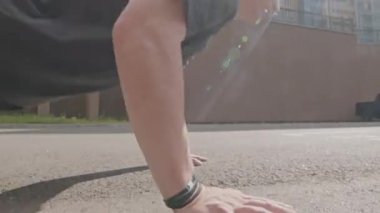 Atletik genç beyaz adamın, dışarıda sabah antrenmanı sırasında asfalt zeminden şınav çekerken elde çekilmiş fotoğrafı.