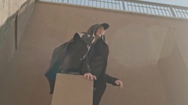 Siyah kapüşonlu beyaz bir adam yazın açık havada park ediyor.