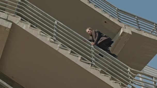 阳光灿烂的日子里 一个年轻的男子爬上高楼的栏杆 拍了一张低角度的照片 — 图库视频影像
