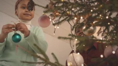 Afrika kökenli Amerikalı 6 yaşında bir kız ve annesi Noel ağacını güzel oyuncaklarla süslemişler.