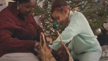 Noel 'de evi dekore ederken annesiyle hasır çantada Noel ağacı oyuncakları ararken orta boy Afrikalı Amerikalı kız fotoğrafı.