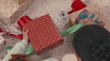 Annesinin renkli ipek kurdeleler takıp Noel hediyelerini evdeki rahat evin zemininde duran kutulara sardığı en iyi manzara.