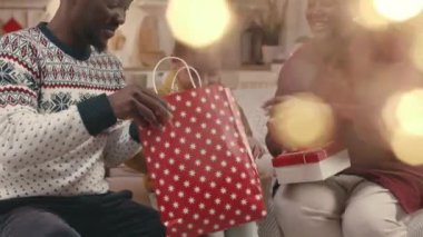 Küçük kızıyla mutlu bir siyahi ailenin Noel 'de güzel, rahat dairelerinde süslemeleriyle hediyelerini verirken orta boy bir fotoğrafı.