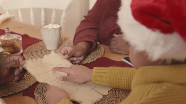 크리스마스 휴일에 부모와 테이블에 앉아있는 모자에 편지를 아프리카계 미국인 소녀의 — 비디오
