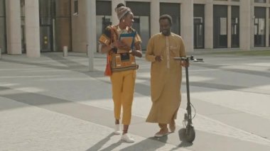 Güneşli bir günde modern ofisten çıkarken çağdaş geleneksel kostümler giyen birkaç genç Afrikalı Amerikalı 'nın tam boy yavaşlığı.