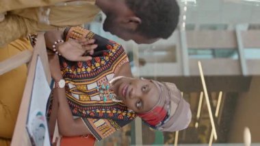 Afrika kökenli Amerikalı iş ortaklarının yaz günü kafenin dışında toplanırken tartışıp sözleşme imzalarken çekilmiş dikey görüntüsü.