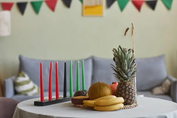 Horizontal image of candles and exotic fruits for Kwanzaa holiday on table in living room