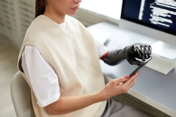 Zbliżenie Młodej Dziewczyny Protezą Ramienia Wpisując Kody Smartfonie Podczas Pracy — Zdjęcie stockowe