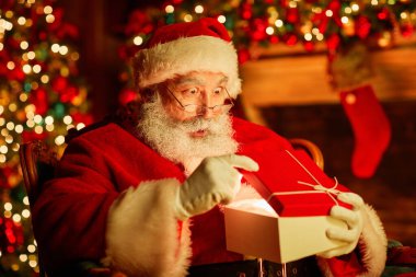 Geleneksel Noel Baba portresi içinde sihirli ışık olan hediye kutusunu açıyor ve şaşırmış görünüyor.