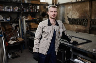 Waist up portrait of professional worker standing in workshop and looking at camera, copy space clipart