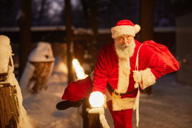 Geleneksel Noel Baba 'nın portresi Noel arifesinde dışarıda çitlerden atlayan hediyelerle dolu.