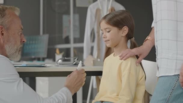 在医院预约治疗后 白人男儿科医生给亚洲小女孩滴鼻水或眼药水 — 图库视频影像