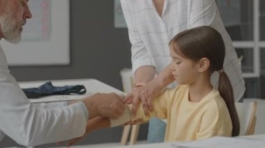 Kafkas erkek doktor beline kadar yaralı küçük kızları hastanede elastik bandajla bandajlıyor.