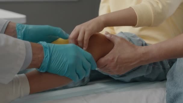 Unbekannter Arzt Weißem Laborkittel Und Blauen Medizinhandschuhen Bandagiert Verletztes Bein — Stockvideo