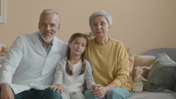 의사와 할머니 사이의 거실에서 소파에 아시아의 소녀의 초상화 카메라에 — 비디오