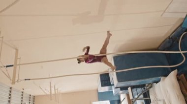 Jimnastikçi kızın spor salonundaki ipe tırmanışını dikey olarak çekiyoruz.
